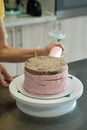 Woman spreads pink cream on cake with pastry bag, close-up. Cake making process, Selective focus Royalty Free Stock Photo