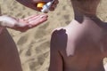 A woman spreads sunscreen on the back and shoulders of the little girl. Royalty Free Stock Photo