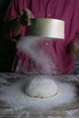 The woman sprinkles the dough from the satiated for the flour, the vocifa bursts and the falling flour. Preparatory process for