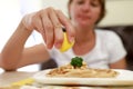 Woman sprinkles fish with lemon juice Royalty Free Stock Photo