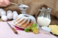 Woman sprinkles a homemade lemon bundt cake with sugar, lemon, melissa, milk, eggs and butter Royalty Free Stock Photo