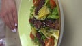 The woman sprinkles the salad with sesame seeds. Vertical video. Close-up. Concept of healthy lifestyle and healthy