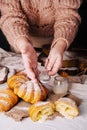 woman sprinkles vanilla croissant with powdered sugar