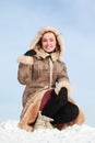 Woman squatting on snow and holds hood hand