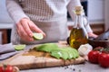 woman squeeze fresh lime juice onto Sliced avocado on wooden cutting board at domestic kitchen Royalty Free Stock Photo