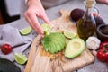 woman squeeze fresh lime juice onto Sliced avocado on wooden cutting board at domestic kitchen Royalty Free Stock Photo