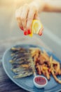 Woman squeeze lemon on portion of fish in a restaurant Royalty Free Stock Photo