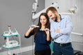 Woman squeezes toothpaste on toothbrush, man looks attentively at process