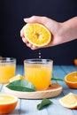 Woman squeezing fresh orange juice on blue table, top view Royalty Free Stock Photo