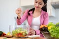 A woman is squeezing a lemon on her healthy salad bowl, making her healthy breakfast in the kitchen Royalty Free Stock Photo