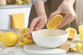 Woman squeezing lemon juice into bowl at marble table, closeup Royalty Free Stock Photo