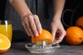 Woman squeezing orange juice at grey table, closeup Royalty Free Stock Photo