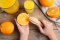 Woman squeezing orange juice at wooden table, top view Royalty Free Stock Photo