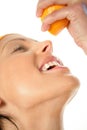 Woman squeezing orange into mouth