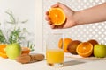 Woman squeezing orange over glass of juice at white wooden table, closeup Royalty Free Stock Photo