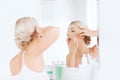 Woman squeezing pimple at bathroom mirror Royalty Free Stock Photo