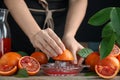 Woman squeezing sicilian orange juice at wooden table, closeup Royalty Free Stock Photo