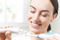 Woman Squeezing Toothpaste Onto Electric Toothbrush In Bathroom Royalty Free Stock Photo