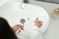 Woman squeezing toothpaste from tube onto electric toothbrush above sink in bathroom, closeup Royalty Free Stock Photo