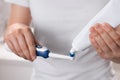 Woman squeezing toothpaste from tube onto electric toothbrush, closeup Royalty Free Stock Photo