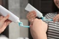 Woman squeezing toothpaste from tube onto toothbrush near mirror in bathroom, closeup Royalty Free Stock Photo