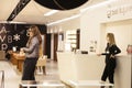 Woman, staff employee worker wearing a facemask in an optician store, while a client doesnt wear any mask during the coronavirus