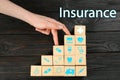 Woman, stairs made with cubes and word INSURANCE on black wooden background