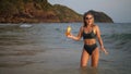 Woman stand knee-deep in sea on sunset. Girl on beach in green s Royalty Free Stock Photo