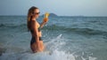 Woman stand knee-deep in sea on sunset. Girl on beach in green s Royalty Free Stock Photo