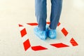 Woman stand in line keeping social distance wearing overshoes, medical shoe covers in Store, supermarket, hospital. People