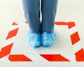 Woman stand in line keeping social distance wearing overshoes, medical shoe covers in Store, supermarket, hospital. People