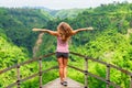 Woman stand on overhanging bridge on high cliff above jungle