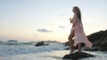 Woman stand on a reef rock stone in sea on sunset. Girl on beach Royalty Free Stock Photo