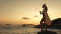 Woman stand on a reef rock stone in sea on sunset. Girl on beach Royalty Free Stock Photo