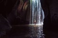 Woman stand under cave waterfall Royalty Free Stock Photo