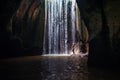 Woman stand under cave waterfall Royalty Free Stock Photo