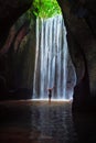 Woman stand under cave waterfall Royalty Free Stock Photo