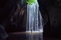 Woman stand under cave waterfall Royalty Free Stock Photo