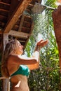 Woman stand under shower in outside bathroom with garden view Royalty Free Stock Photo