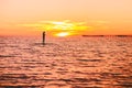 Woman stand up paddle boarding at dusk on a quiet sea with beautiful sunset Royalty Free Stock Photo