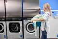 side view on young woman standing alone with dirty clothes in the self serviced laundry with dryer machines Royalty Free Stock Photo