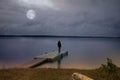 Woman standing alone on the dock of a lake under the moon light Royalty Free Stock Photo