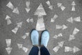 Woman standing on asphalt road with arrows pointing in different directions. Concept of choice