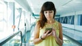 Woman standing on Automatic walkway, stairs in subway crossing, using her phone, a mean of communication, a fashionable Royalty Free Stock Photo