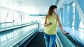 Woman standing on Automatic walkway, stairs in subway crossing, using her phone, a mean of communication, a fashionable Royalty Free Stock Photo