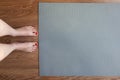 Woman is standing barefoot on floor in front of gymnastic mat, she is going to do morning exercise complex. Only legs are visible Royalty Free Stock Photo