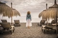 Woman standing at the beach alone looking at the ocean - tourism and winter sea travel vacation - one female adult viewed from