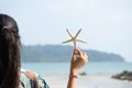 Woman standing on the beach in summer with starfish in hand