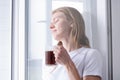 Woman Standing By Bedroom Window And drinking fresh coffee Royalty Free Stock Photo