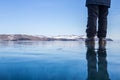 Woman standing on blue ice of frozen lake Baikal with reflection